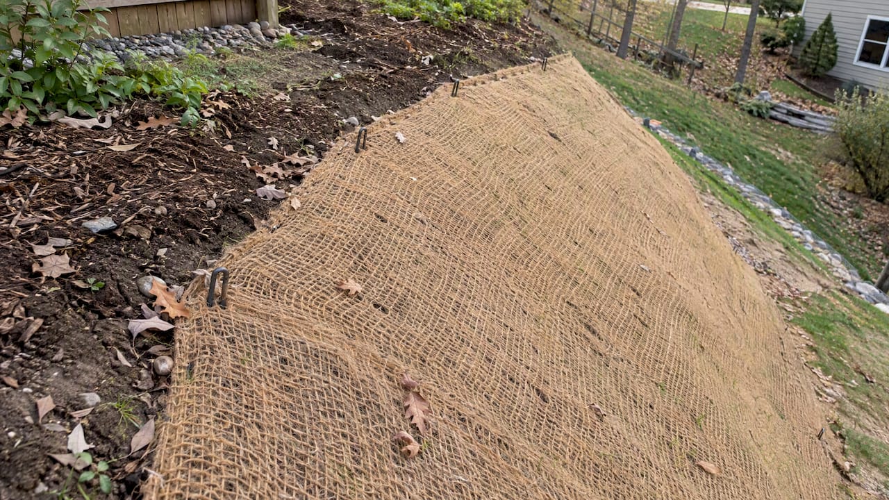 Erosion blanket pinned tightly against sloping soil